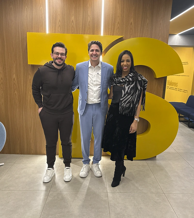 Renan Nicolini ao lado de dois convidados diante do letreiro do Grupo TS, na sede da empresa