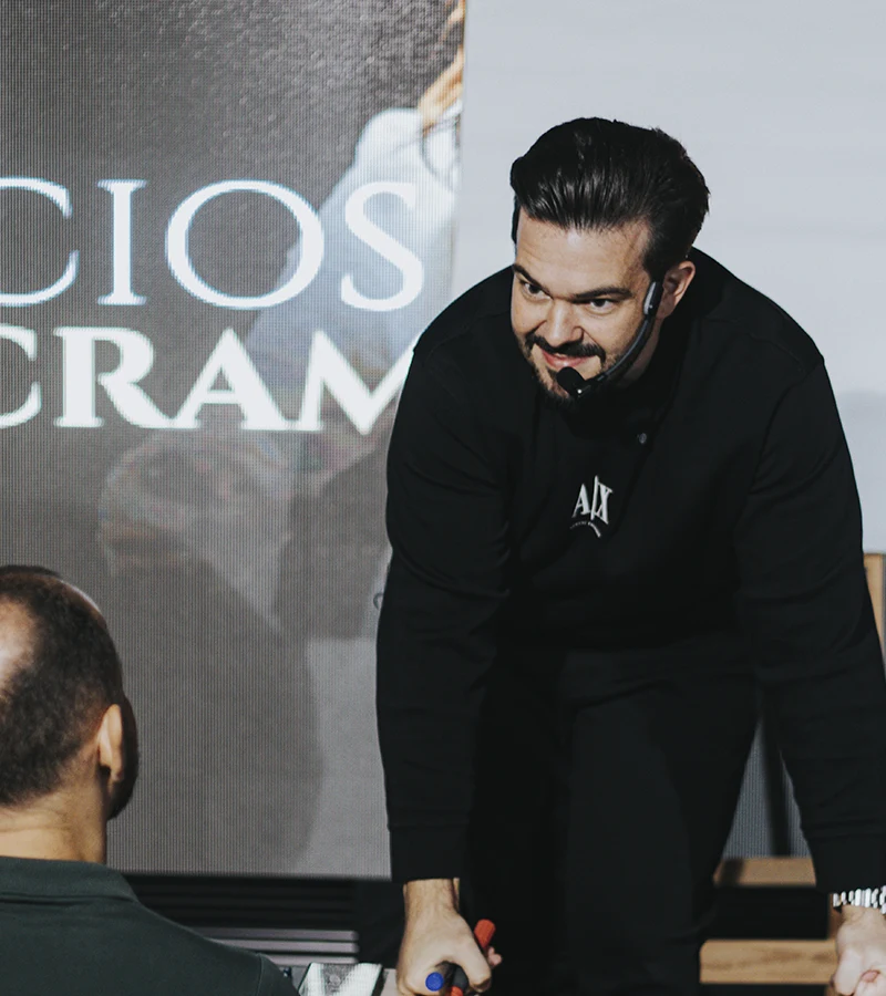 Renan Nicolini inclinado sobre a mesa, conversando de perto com um participante